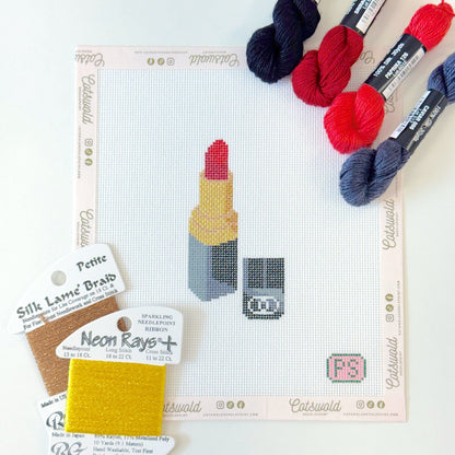 Red lipstick makeup needlepoint canvas flat lay with specialty fibers and coordinating threads